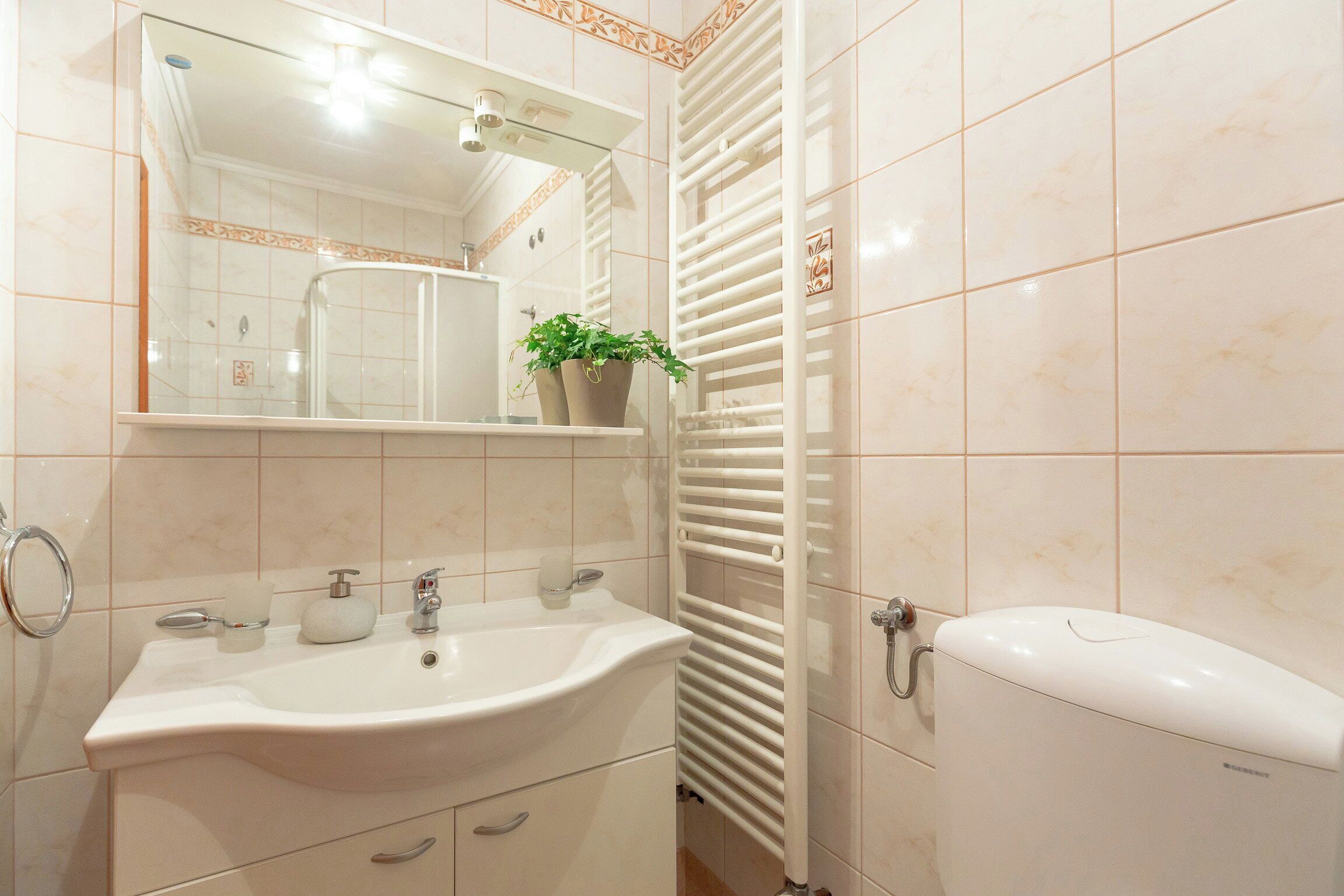 A bathroom with a sink, mirror, toilet, and radiator.