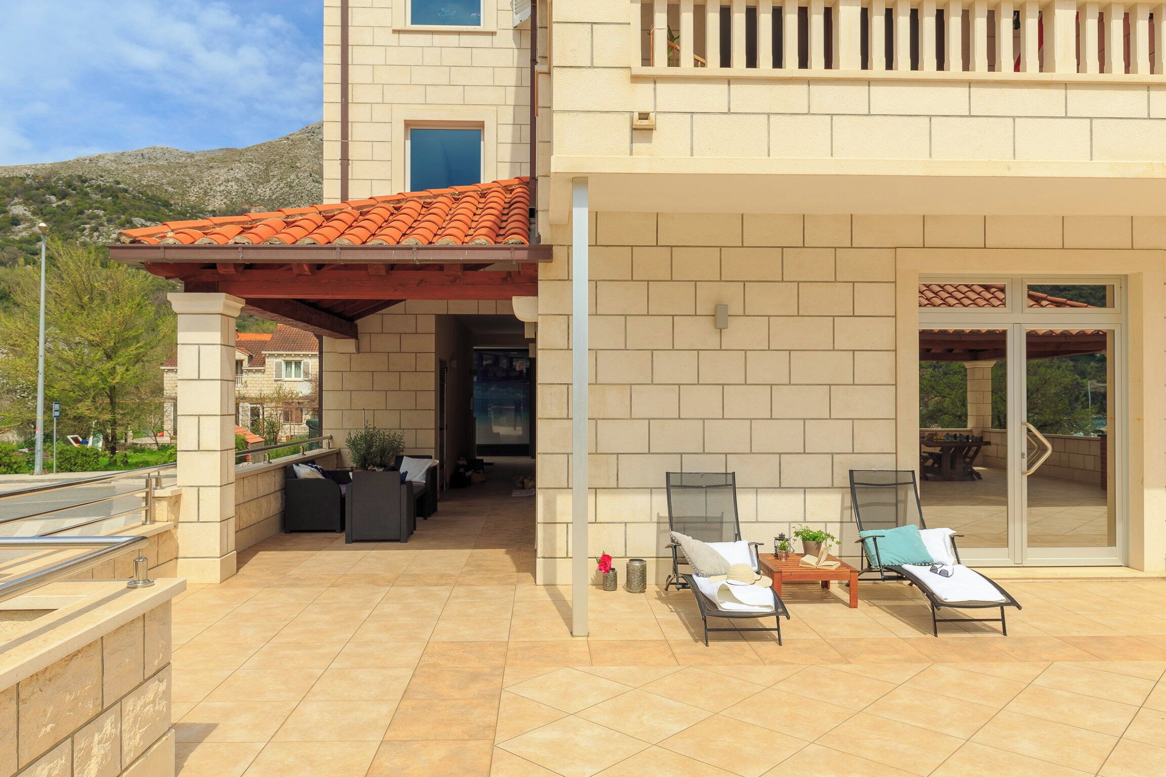 Un'area esterna coperta con patio, due poltrone, un tavolo e una piccola pianta in vaso.