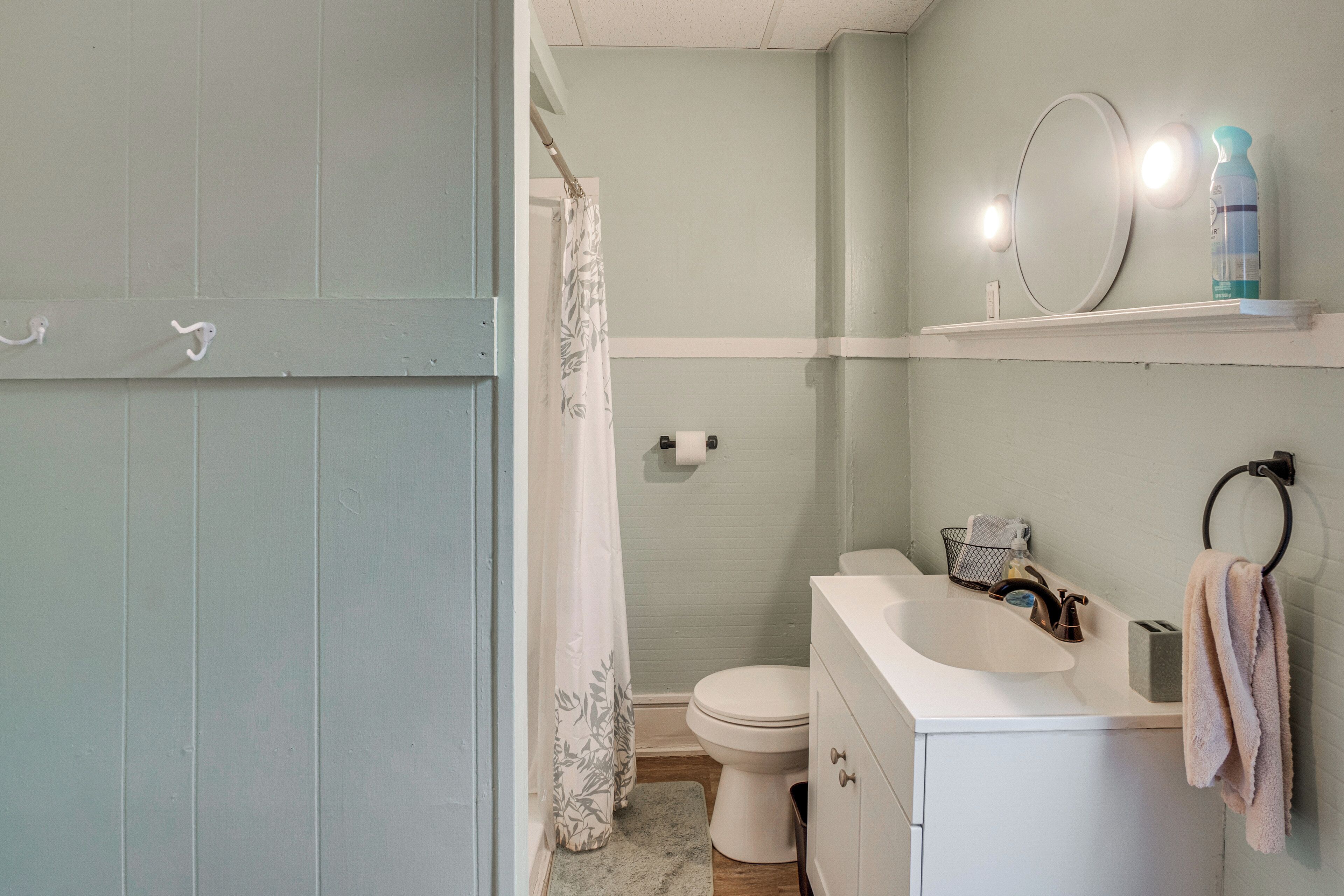 A bathroom with a toilet, sink, mirror, and shower curtain.