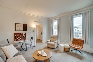 A living room with a sofa, armchairs, a coffee table, a board game, and a lamp. - Walk to Lake Ontario, Shops & Eats! Charming Home (Oswego)