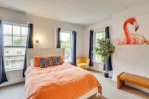 A bedroom with a bed, a bench, a chair, a potted plant, and a painting of a flamingo. - Walk to Lake Ontario, Shops & Eats! Charming Home (Oswego)