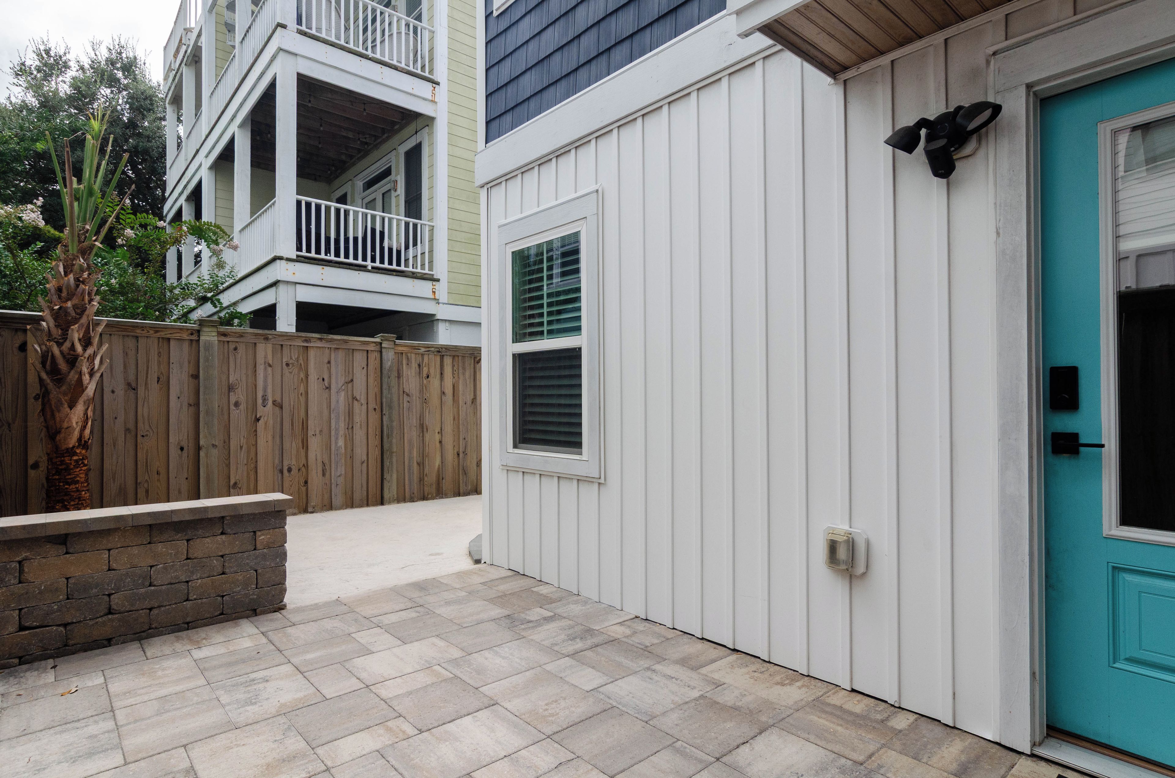 A residential building with a garage door, a wooden fence, and a stone planter.