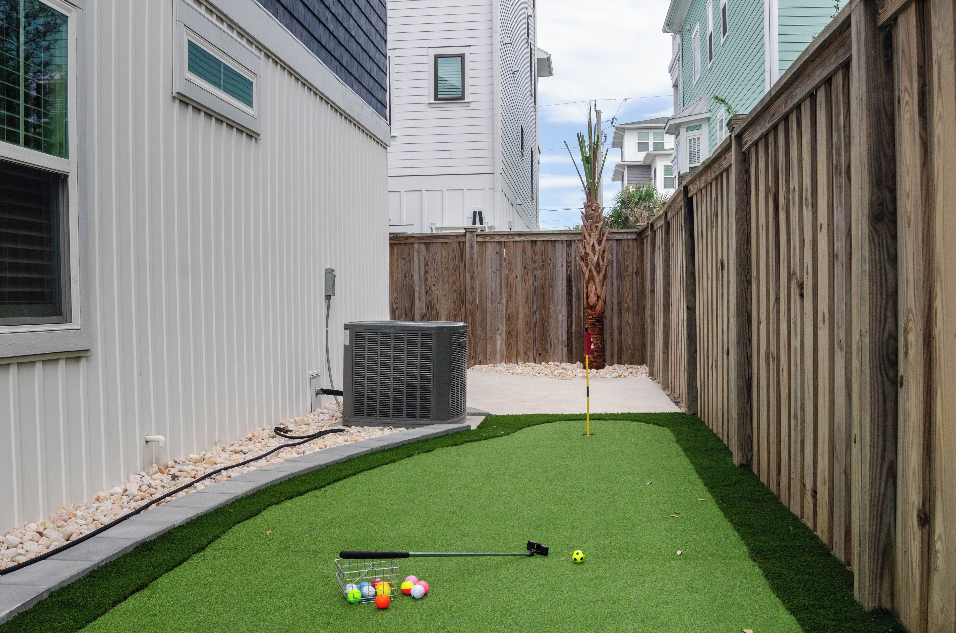 A backyard with artificial grass, a golf hole, and a flagstick.