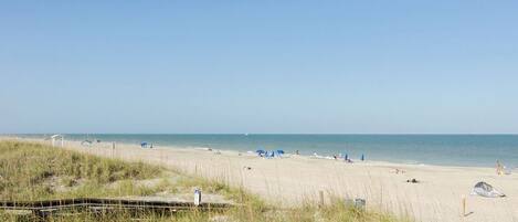 Ein Strand mit einer Holzpromenade, Strandstühlen und Zelten.