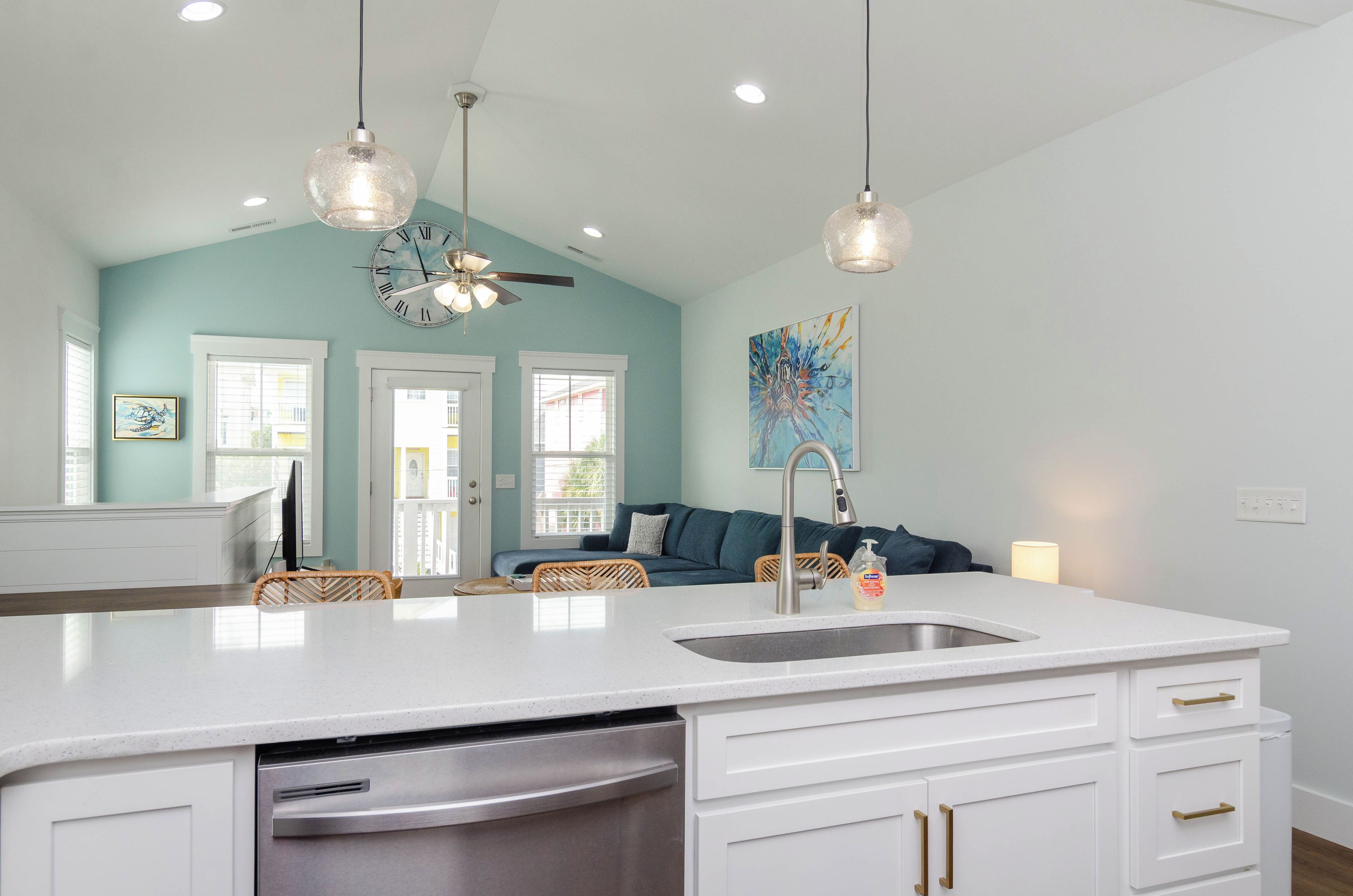 A modern kitchen with a central island, white cabinetry, and a built-in dishwasher.