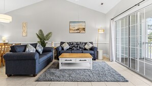 A living room with a grey sofa, a wooden coffee table, and a large window with a view. - Coastal Retreat at Myrtlewood (Myrtle Beach)