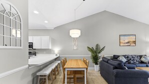 Een moderne keuken met witte kasten, een houten eettafel en een blauwe bank in een woonruimte.