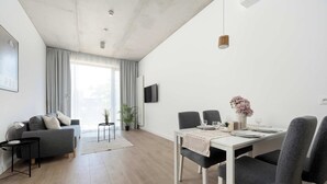 Una sala de estar moderna con sofá, mesa de comedor, sillas y televisor.
