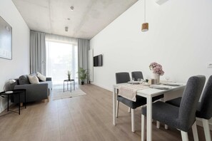 Ein modernes Wohnzimmer mit einer Couch, einem Esstisch, Stühlen und einem Fernseher.