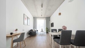 Una sala de estar moderna con sofá, mesa de comedor, sillas y televisor.