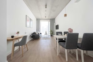 Ein modernes Wohnzimmer mit einer Couch, einem Esstisch, Stühlen und einem Fernseher.