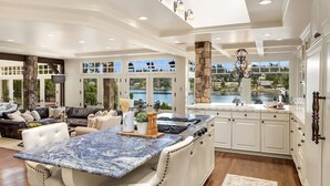 A spacious kitchen with a large island, white cabinetry, and a view of a lake. - Hunts Point | Waterfront Estate & Guest Villa (Hunts Point)