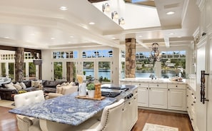 A spacious kitchen with a large island, white cabinetry, and a view of a lake. - Hunts Point | Waterfront Estate & Guest Villa (Hunts Point)