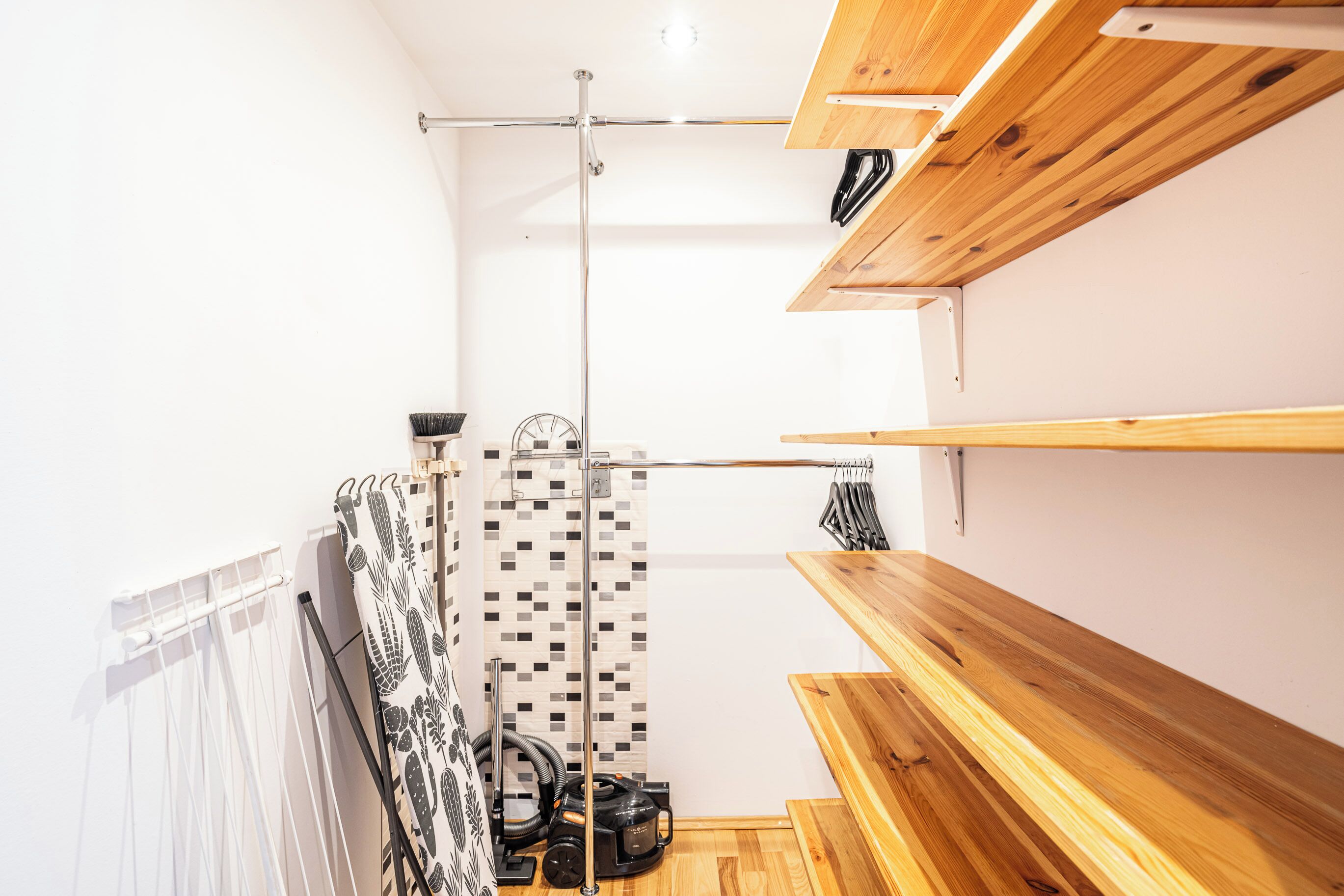 A room with a wooden bench, a hanging rack, and a vacuum cleaner.