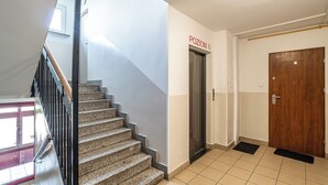 Una escalera que conduce a un ascensor en un pasillo con una puerta de madera y una barandilla de metal.