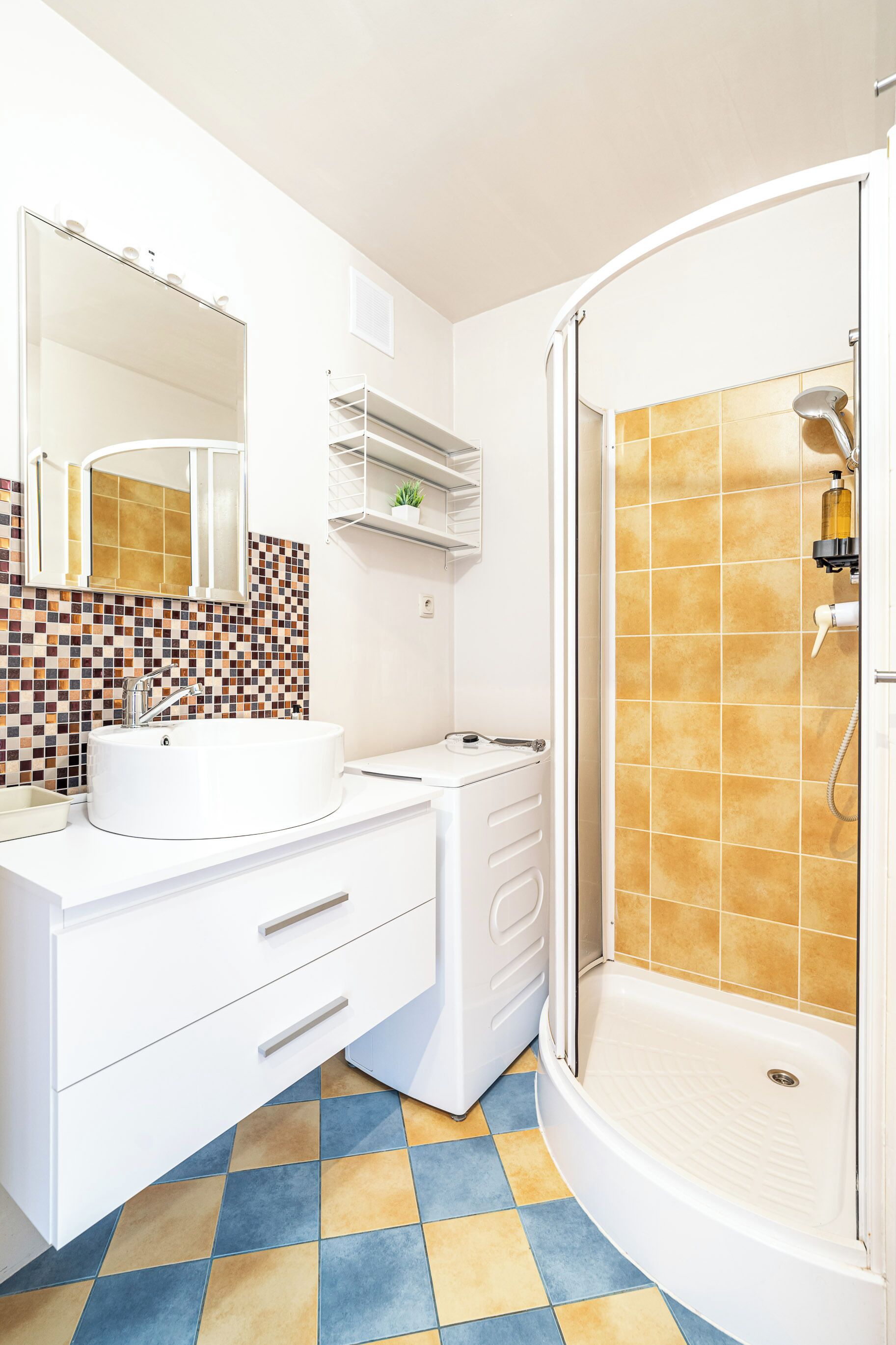 Un baño con lavamanos blanco, espejo y ducha.