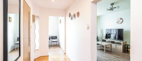 A modern interior with a wooden floor, a dining area with a TV, and a hallway leading to another room.