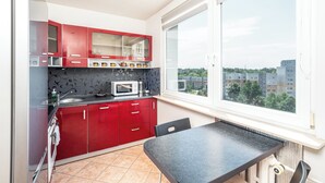 Cocina con armarios rojos, microondas y ventana con vista a la ciudad.