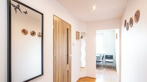 Un pasillo con una puerta de madera, un espejo y obras de arte en la pared.