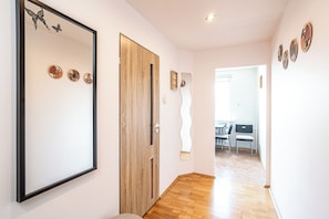 A hallway with a wooden door, a mirror, and wall art. - RentPlanet - Apartament Radockiego (Katowice)