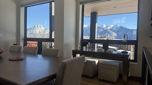 Ein Konferenzraum mit einem großen Tisch, Stühlen und Blick auf schneebedeckte Berge durch große Fenster.