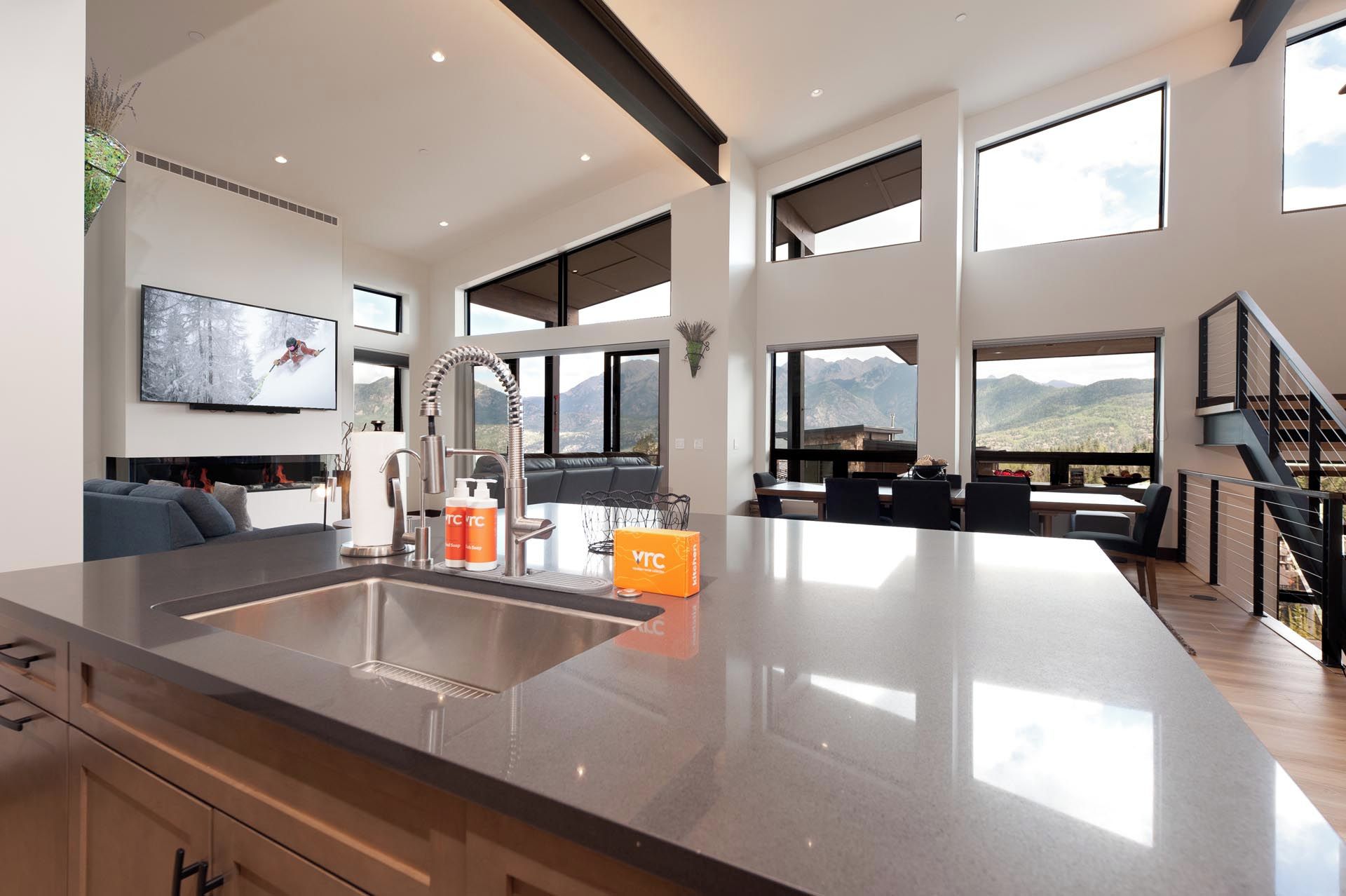 Una cocina moderna con una isla grande, un área de comedor con vistas y una sala de estar con chimenea.