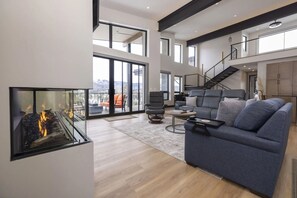 Ein geräumiges Wohnzimmer mit Kamin, einer Couch und einer Treppe, die in eine obere Etage führt.