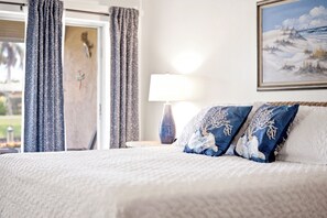 Ein Bett mit weißer Bettwäsche, einer Lampe und einem Bild an der Wand.
