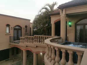 A building with a balcony, a hot tub, and a palm tree.