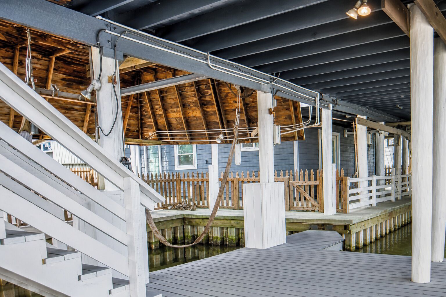 A wooden deck with a railing, a wooden fence, and a water body.