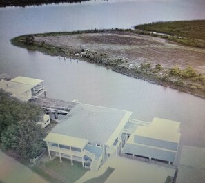 An aerial view of a building with a large water body in front, surrounded by greenery.