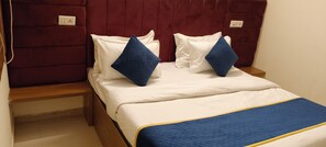 Una cama con ropa de cama blanca, almohadas azules y una colcha acolchada azul.