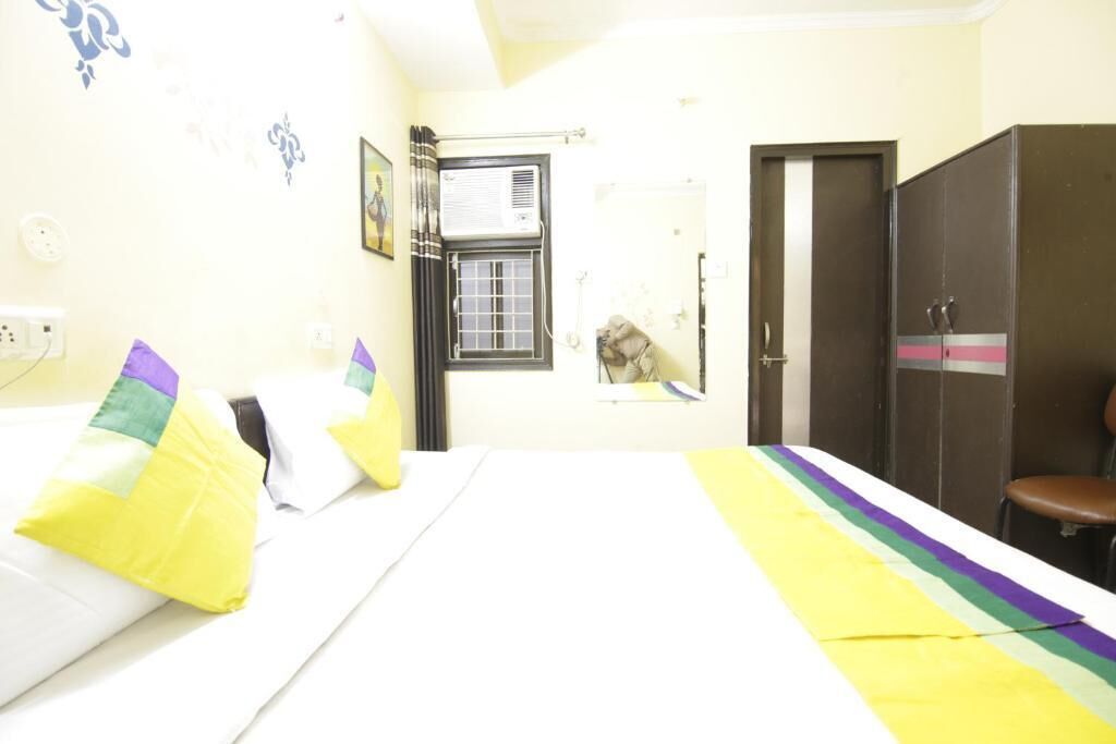 Habitación de hotel con cama, armario, ventana y unidad de aire acondicionado.