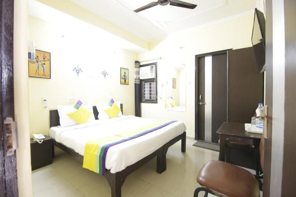 Ein Hotelzimmer mit einem Bett, einem Schreibtisch, einem Stuhl, einem Kleiderschrank und einem Deckenventilator.