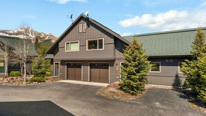 A two-story house with a garage, a satellite dish, and a mountain in the background. - 3BR Ski-In/Out Condo, Nordic Trails, Free Shuttle Access – Big Sky, MT (Big Sky)