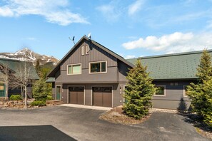 Ein zweistöckiges Haus mit Garage, Satellitenschüssel und Bergen im Hintergrund.