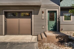 A modern building with a double garage door, a green door, and a mailbox with the number 57. - 3BR Ski-In/Out Condo, Nordic Trails, Free Shuttle Access – Big Sky, MT (Big Sky)