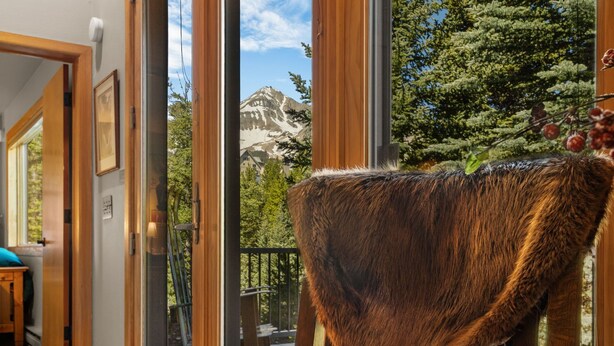 A room with a large window, a wooden chair, and a view of a mountain. - 3BR Ski-In/Out Condo, Nordic Trails, Free Shuttle Access – Big Sky, MT (Big Sky)