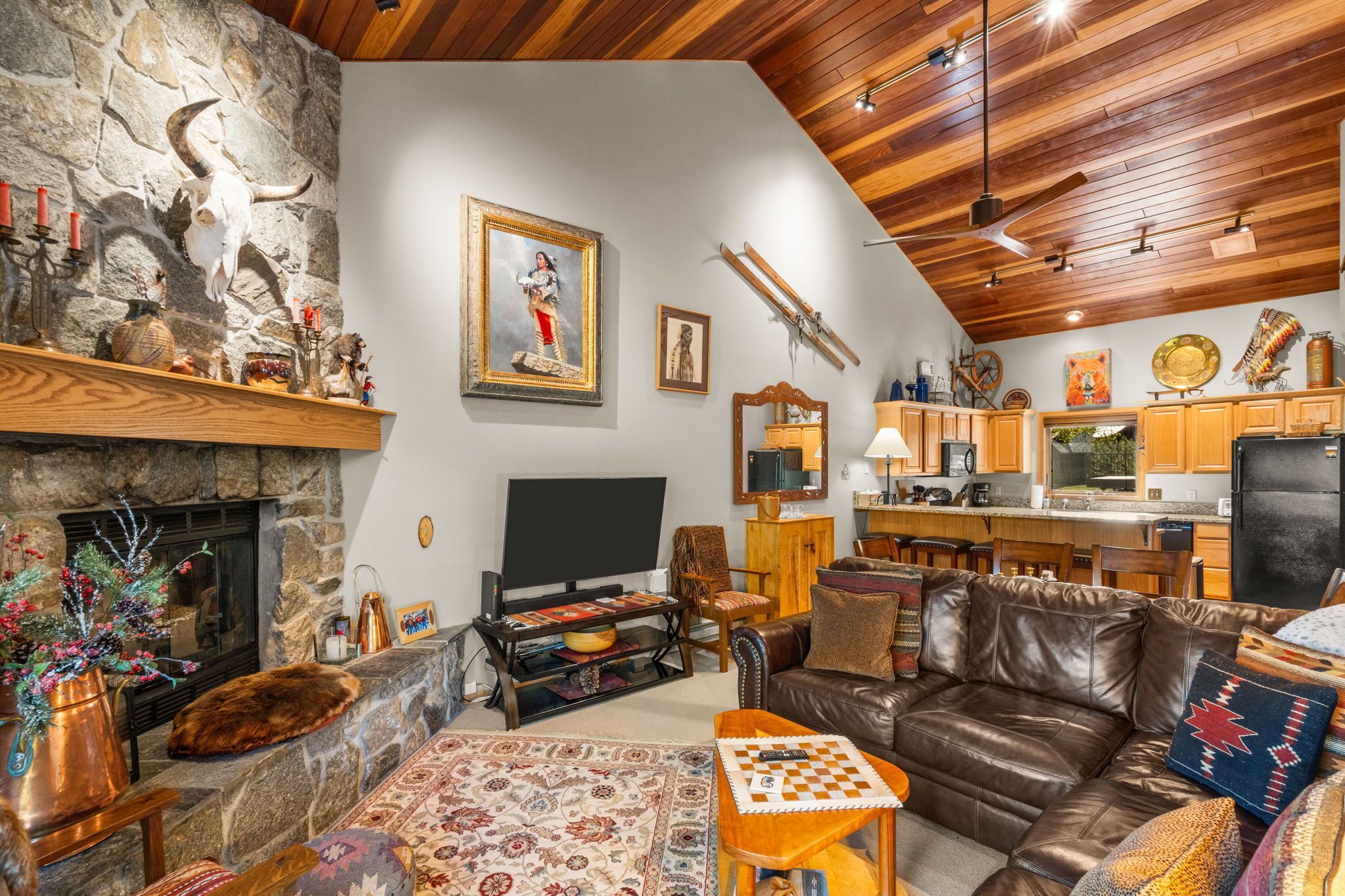 A cozy living room with a fireplace, leather sofa, and a television.