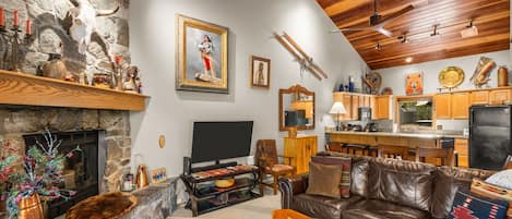 Un salon chaleureux avec une cheminée, un canapé en cuir et un téléviseur.