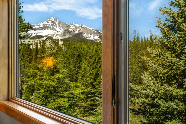 A mountain view through a window with a building in the background. - 3BR Ski-In/Out Condo, Nordic Trails, Free Shuttle Access – Big Sky, MT (Big Sky)