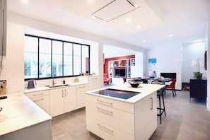 A modern kitchen with a large window, a dining area with a red accent wall, and a living space with a fireplace.