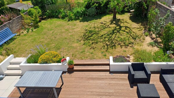 A rooftop terrace with a wooden deck, outdoor seating, and potted plants.