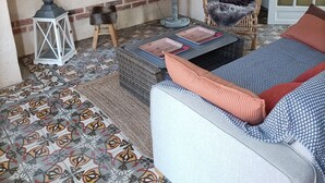 A cozy room with a brick wall, a wicker sofa, a patterned floor, and a door with glass panels.