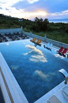 Una piscina al aire libre, sillones reclinables de piscina