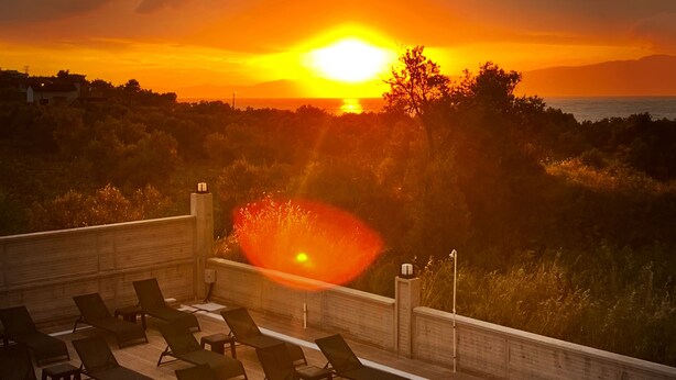 Una piscina en la azotea con sillones de descanso y vista al atardecer.