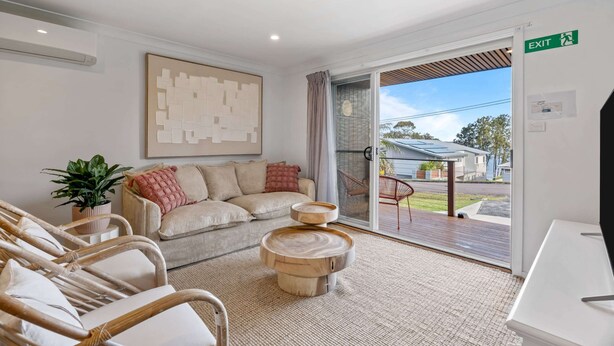 A modern interior with a sofa, chairs, a coffee table, a potted plant, and a view through a glass door. - Relaxed 2 Bed Coastal Stay Near the Lake (Buff Point)