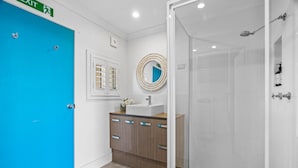 A bathroom with a blue door, a sink, a mirror, and a shower. - Relaxed 2 Bed Coastal Stay Near the Lake (Buff Point)
