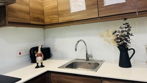 Eine Küche mit Holzausstattung, einem Edelstahlspülbecken, einer schwarzen Karaffe und einer Zimmerpflanze.