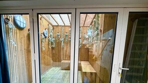 Ein Zimmer mit einer Schiebeglastür, die auf einen Außenbereich mit Holzterrasse und Bank führt.